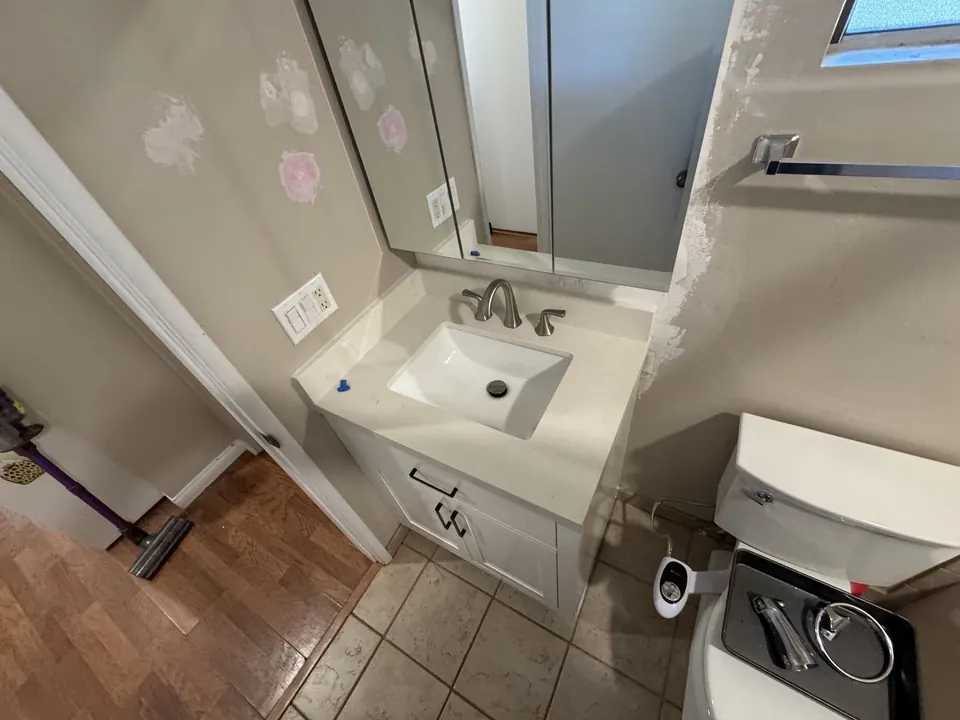 White bathroom vanity with sink installed below a mirror