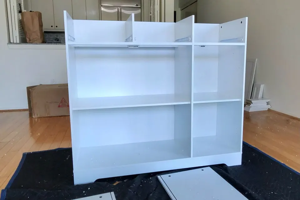 White bookcase partway through assembly, panels and hardware laid out