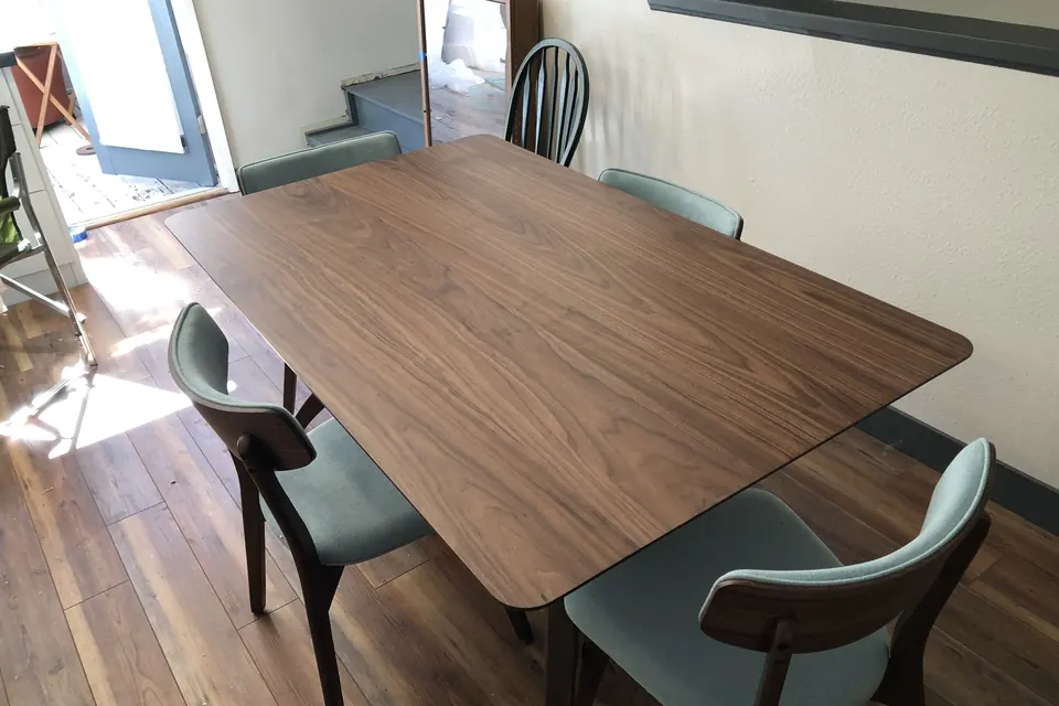 Walnut dining table and teal chairs assembled in a dining room