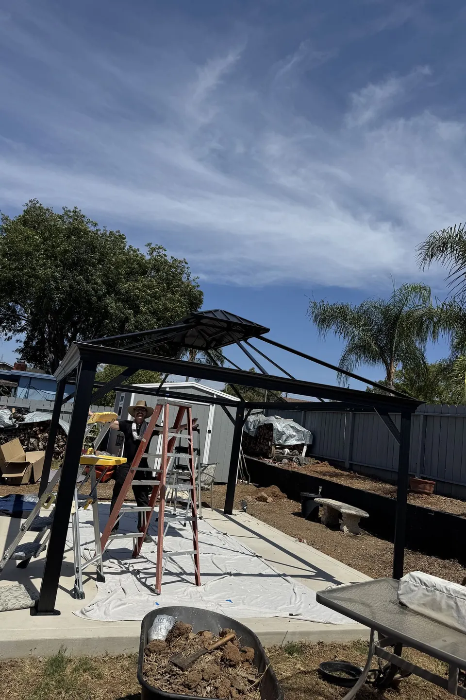 Gazebo partly assembled on a patio under a blue sky