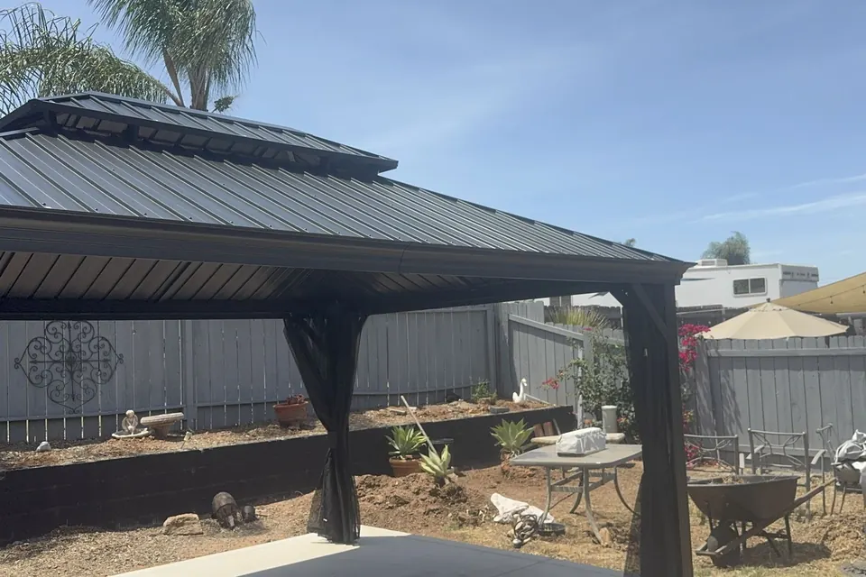 Hardtop gazebo assembled on a backyard patio, palm trees behind