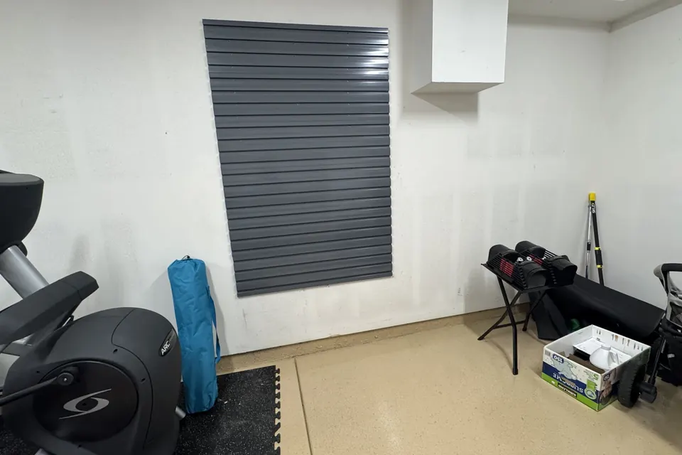 Grey slatwall panel mounted on the wall of a home gym