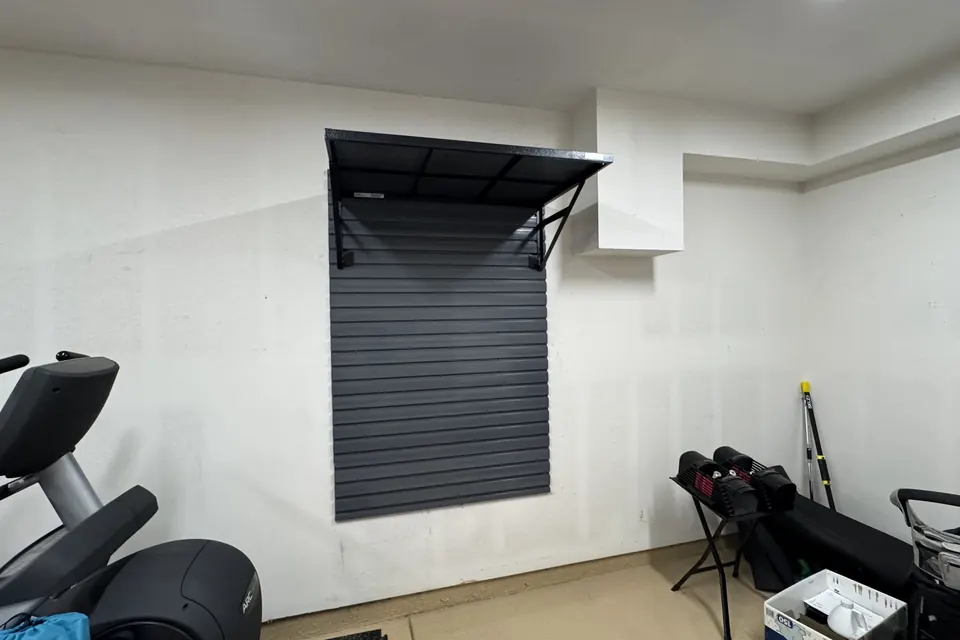 Slatwall panel with overhead shelf installed in a home gym