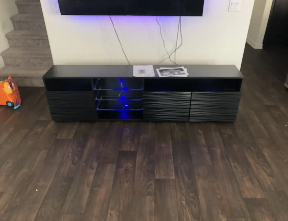 Black TV stand with LED lighting assembled under a TV