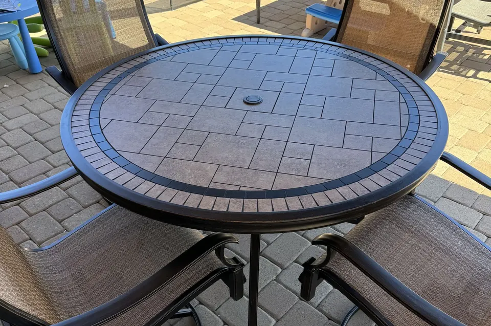 Round mosaic patio table and swivel chairs assembled by a pool