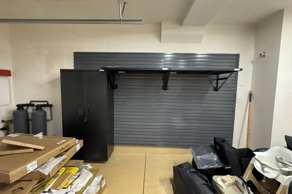 Slatwall with mounted shelf brackets and a cabinet in a garage